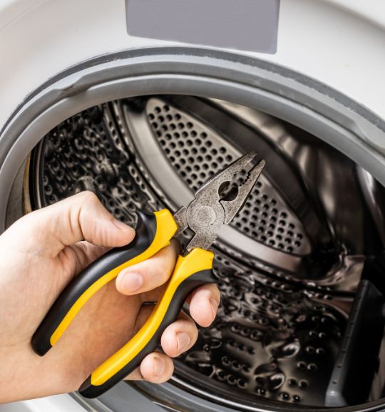 A person with pliers attempting to open a washing machine, symbolizing laundry appliance repair services in San Jose, CA.