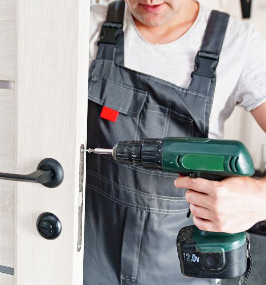 A man in overalls grips a drill and screwdriver, illustrating small appliance repair services available in San Jose, CA.