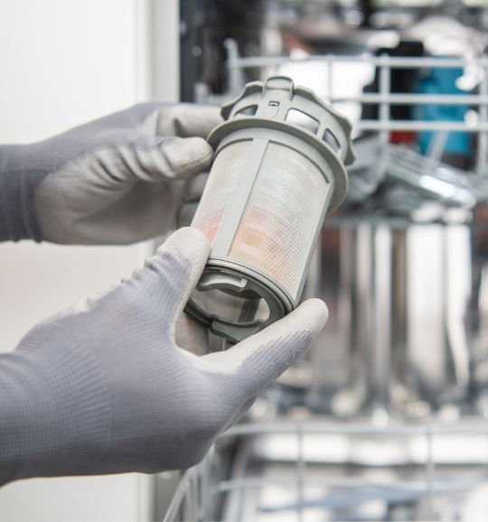 A person in gloves is displaying a dishwasher filter, highlighting appliance repair services available in San Jose, CA.